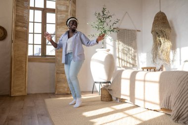 Açık renk elbiseli Afrikalı kadın evde vakit geçiriyor.