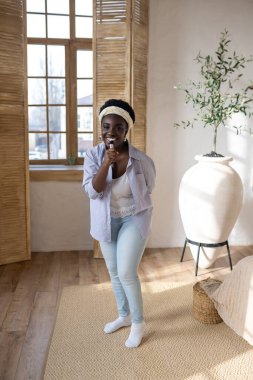 Afro-Amerikan kadın makyaj yapıyor ve ilgili görünüyor.