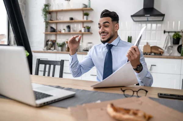 An excited man sitting at the laptop and having a vieo call — 스톡 사진