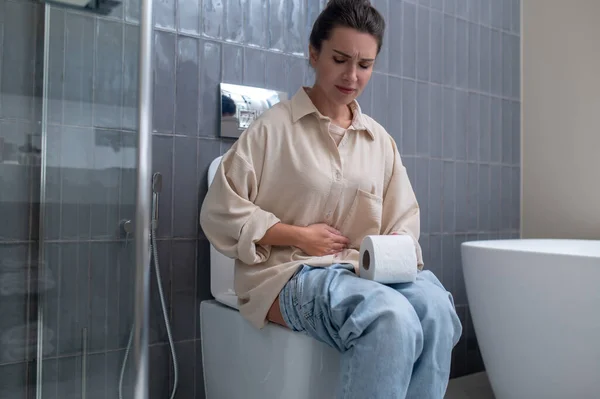 Seorang wanita muda duduk di toilet — Stok Foto