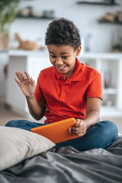 Niño en camiseta naranja mirando emocionado mientras ve algo en línea —  Fotos de Stock