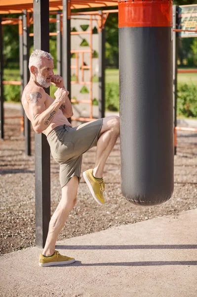 A mature gray-haired man exercising in the park — Stockfoto