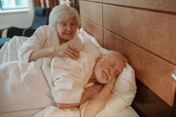 Старшая пара в постели утром в номере отеля — стоковое фото