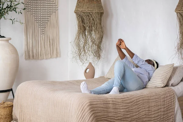 Afro-Amerikalı kadın yatakta uzanıyor ve rahatlamış görünüyor.