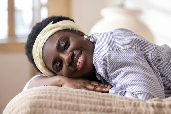 Африканська американка лежить на ліжку і виглядає замріяною. — стокове фото