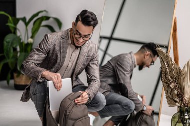 İşe gitmeden önce sırt çantasını alan şık bir adam.