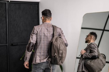 Daireyi terk eden sırt çantalı bir adam.