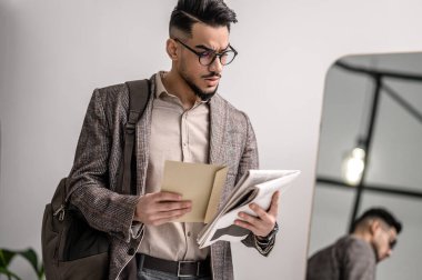 A man in a stylish jacket with some papers in hands
