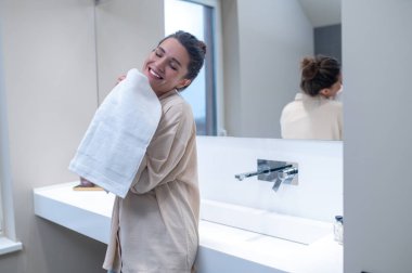 Gülümseyen kadın mutlu görünüyor ve elinde temiz bir havlu tutuyor.