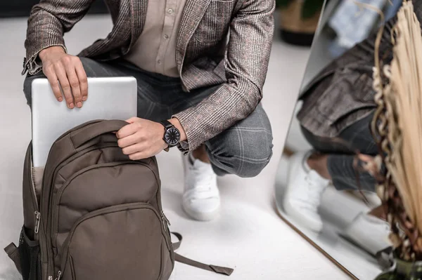 A stylish man apacking his backpack before leaving to work — Stockfoto