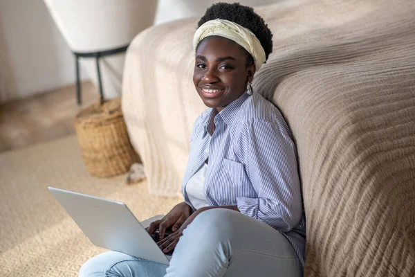 African american woman sitting on the sofa and spending time in chat online — Photo
