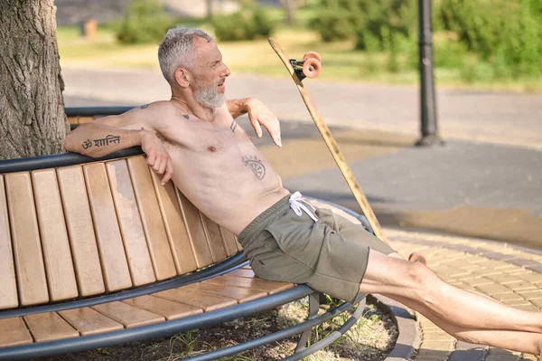 Un hombre sentado en el banco después de hacer ejercicio en el parque — Foto de Stock
