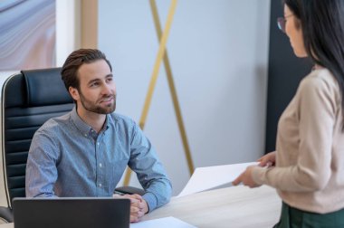 Gülümseyen CEO, ofisindeki kadın sekreterle iletişim kuruyor.