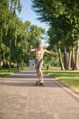 A male skateboarder riding a skateboard and keeping balance