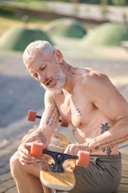 Oturup kaykayının detaylarını düzelten bir adam.