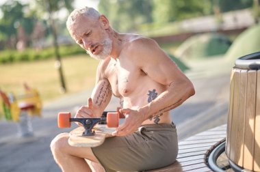 Oturup kaykayının detaylarını düzelten bir adam.