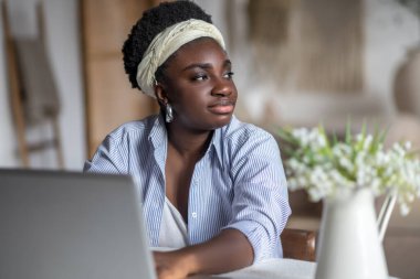 African american woman sitting at the table and working on a laptop