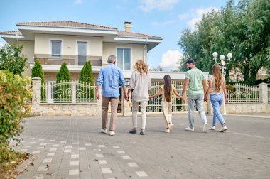 Büyük bir aile el ele yürüyor ve mutlu görünüyor.