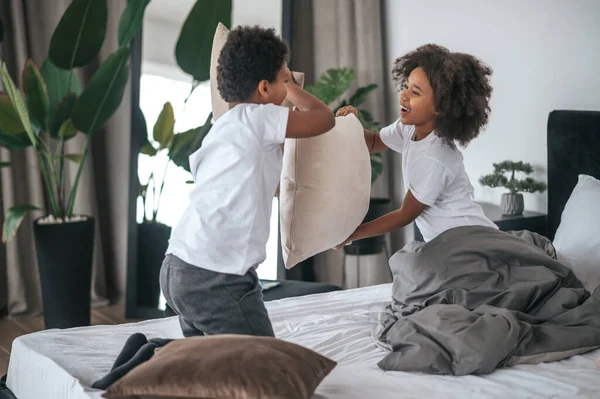 Siblings spending time at home and playing with pillows — Stockfoto