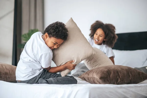 Siblings spending time at home and playing with pillows — Stockfoto