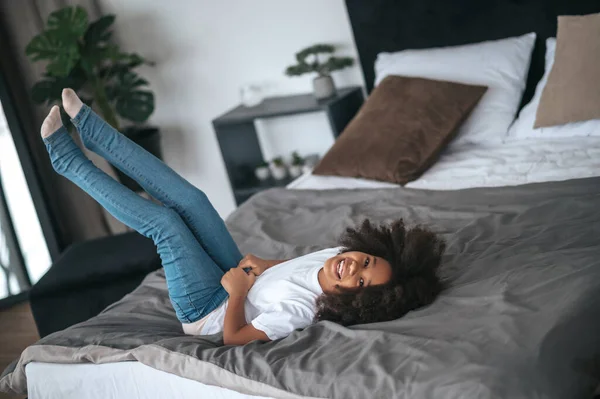 A cute curly-haired girl having fun and looking enjoyed — Foto de Stock