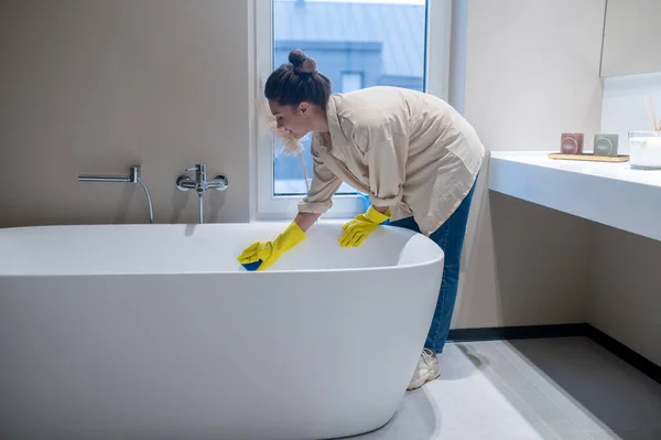 Una mujer haciendo limpieza en casa y desinfectando el baño —  Fotos de Stock