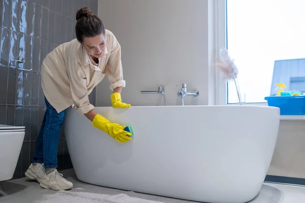 En kvinna städar hemma och desinficerar badrummet. — Stockfoto