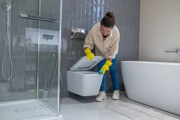 Yung housewife looking busy while cleaning in the bathroom —  Fotos de Stock