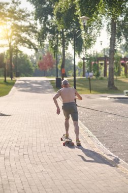 Bir erkek kaykaycı parkta gezintiden zevk alıyor.