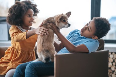 Bir erkek ve bir kız bir köpek yavrusuyla oynuyorlar.