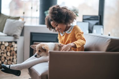 Koyu tenli kız sevimli bir köpekle oynuyor.