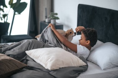 Yatakta yatan bir çocuk ve yanında bir köpek.