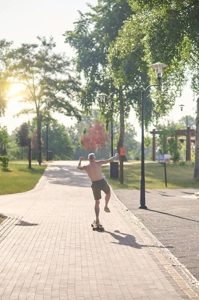Un skateboarder masculin profitant d'une balade dans un parc — Photo
