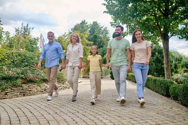 Famiglia sorridente che cammina mano nella mano e sembra felice — Foto Stock