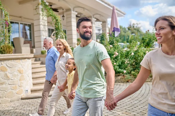 Gülümseyen aile el ele yürüyor ve mutlu görünüyor.