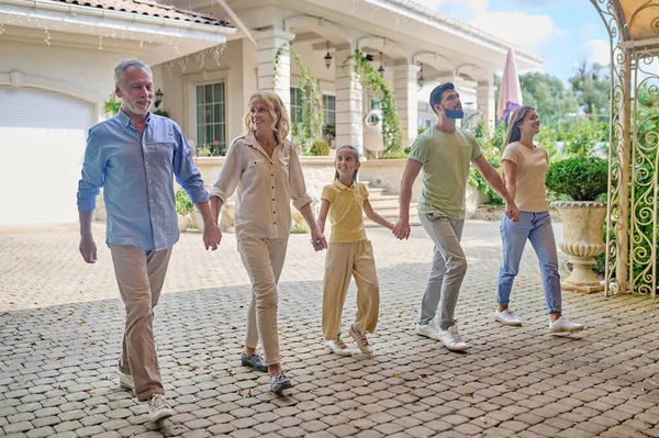Famiglia sorridente che cammina mano nella mano e sembra felice — Foto Stock