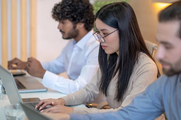 Focused company worker and her coworkers working on their laptops — Foto de Stock