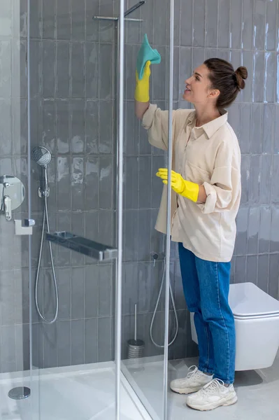 Mujer joven limpiando la cabaña de sahower y buscando involucrado —  Fotos de Stock