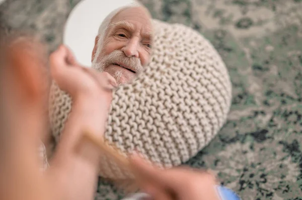 Δυσαρεστημένος ηλικιωμένος άνδρας που εξετάζει την αντανάκλασή του στον καθρέφτη — Φωτογραφία Αρχείου