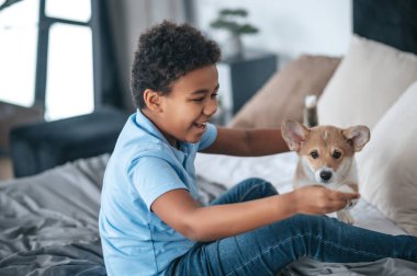 Köpeğiyle eğlenen ve heyecanlı görünen bir çocuk.