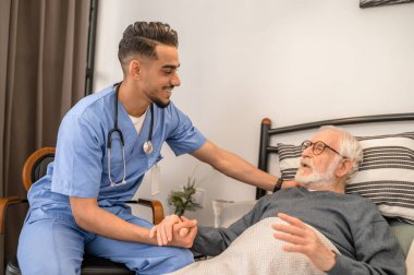 Smiling friendly doctor visiting a bedridden patient