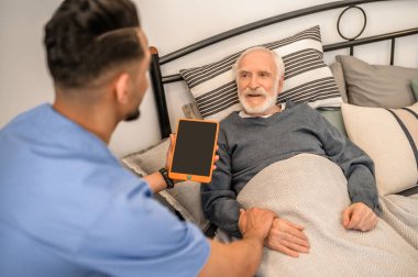 Doktor ev ziyareti sırasında yatalak bir hastayı muayene ediyor.