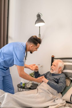 In-home nurse assisting the patient into a sitting position