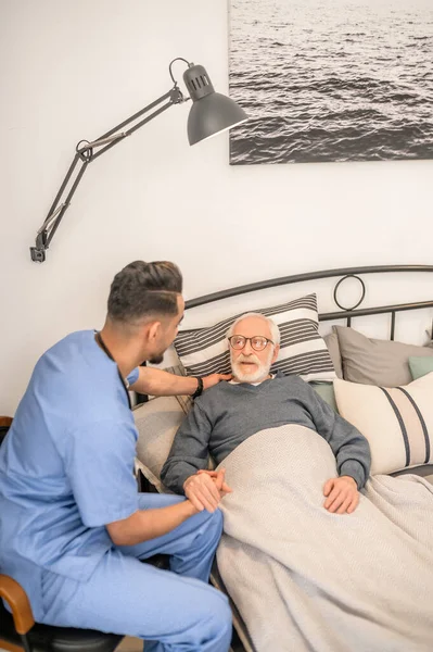 Чоловік лікар відвідує хворого літнього чоловіка — стокове фото