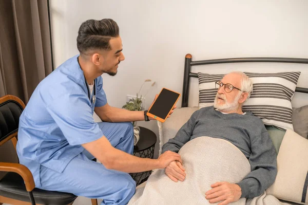 Médico general examinando a un hombre postrado en cama durante la visita domiciliaria — Foto de Stock