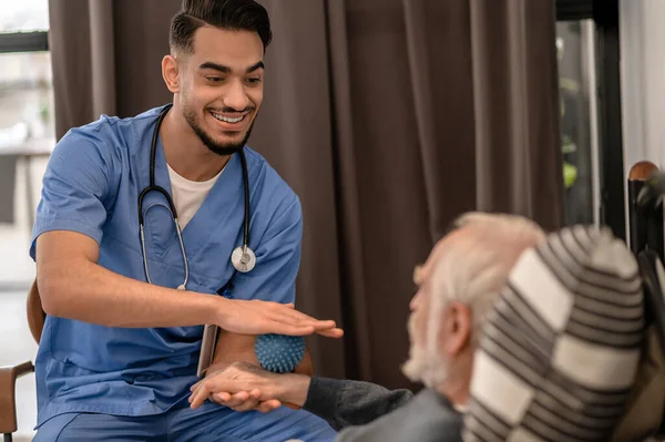 Smiling friendly physiatrist conducting an in-home physiotherapy session —  Fotos de Stock