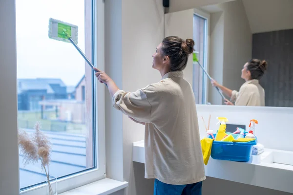 Young woman cleaning the window in the bathroom —  Fotos de Stock