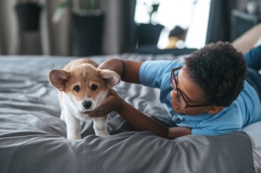 Gülümseyen çocuk köpek yavrusuyla oynuyor ve mutlu görünüyor.