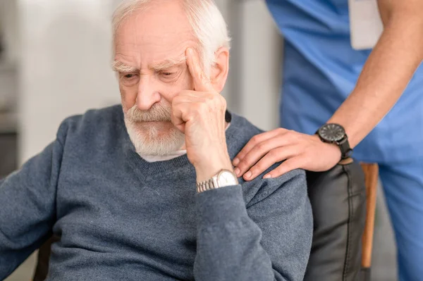 Низкодуховный пожилой человек утешается своим сиделкой — стоковое фото