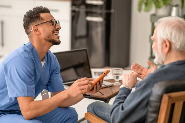 Volunteer enjoying his communication with an aged person — Stock Photo, Image